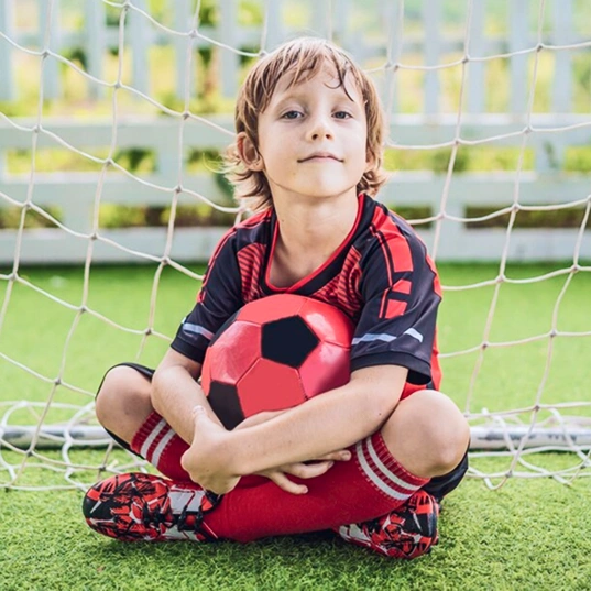 Kid Sitting While Holding a Red Soccer Ball
